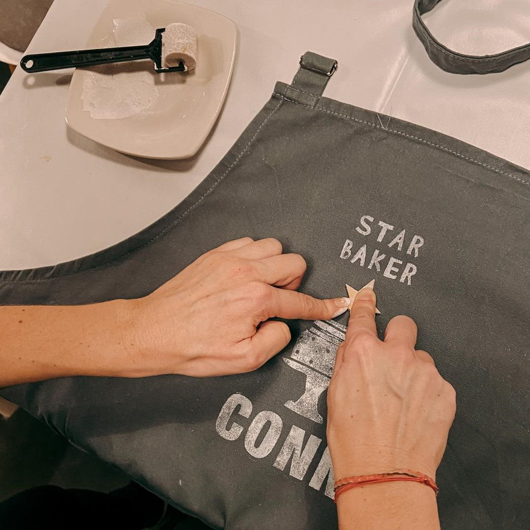 Zwei Hände stempeln Stern auf Stoff, Rolle im Hintergrund – diy textildruck, stempel kunst, stoff bedrucken, auch für Firmenevents.