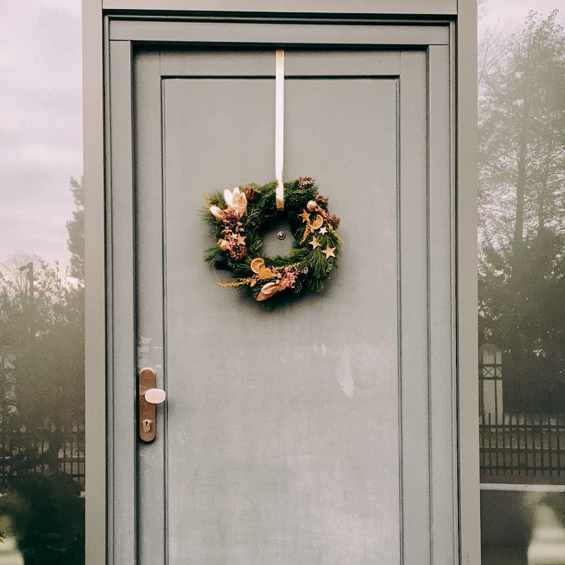 Tür mit hängendem Weihnachtskranz, gesamte Tür im Blick – weihnachtskranz tür, weihnachtsworkshop berlin, auch für Firmenevents.