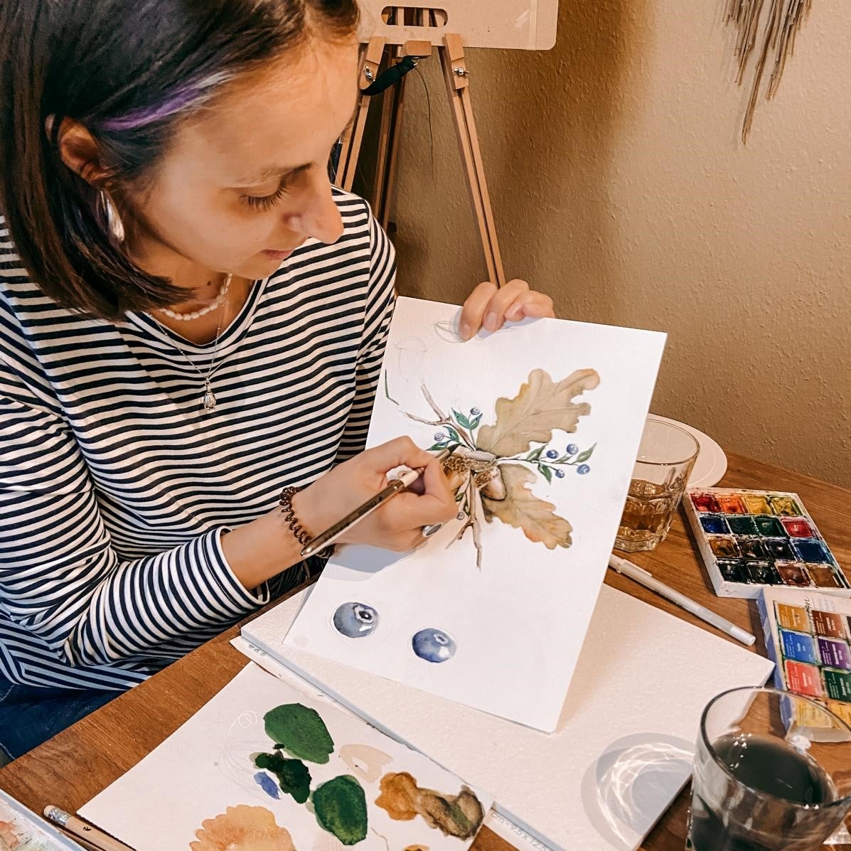 Frau zeigt Bild beim Malen – Aquarell Workshop Herbst, Tipps zu Farbmischungen.