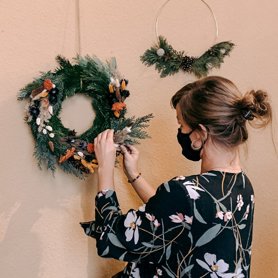 Frau arbeitet an hängendem Kranz an der Wand – diy weihnachtskranz, weihnachtsworkshop berlin, auch für Firmenevents.
