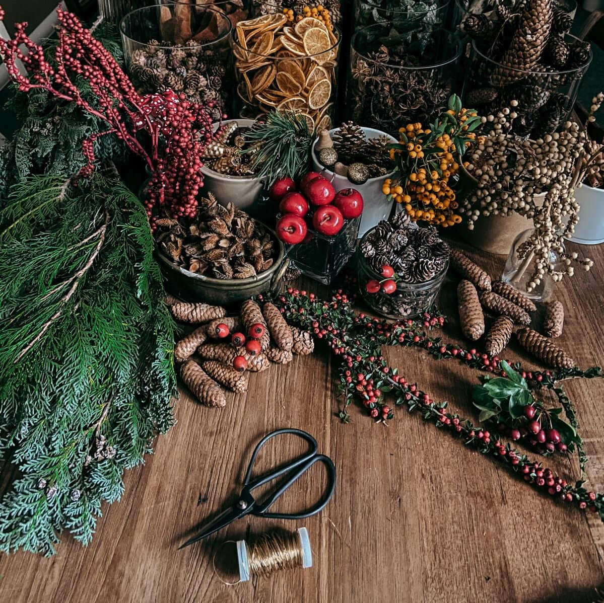 Tisch mit Materialien wie Tannenzweigen, Kugeln und Schleifen – adventskranz ideen.Auch als Firmenevent buchbar.