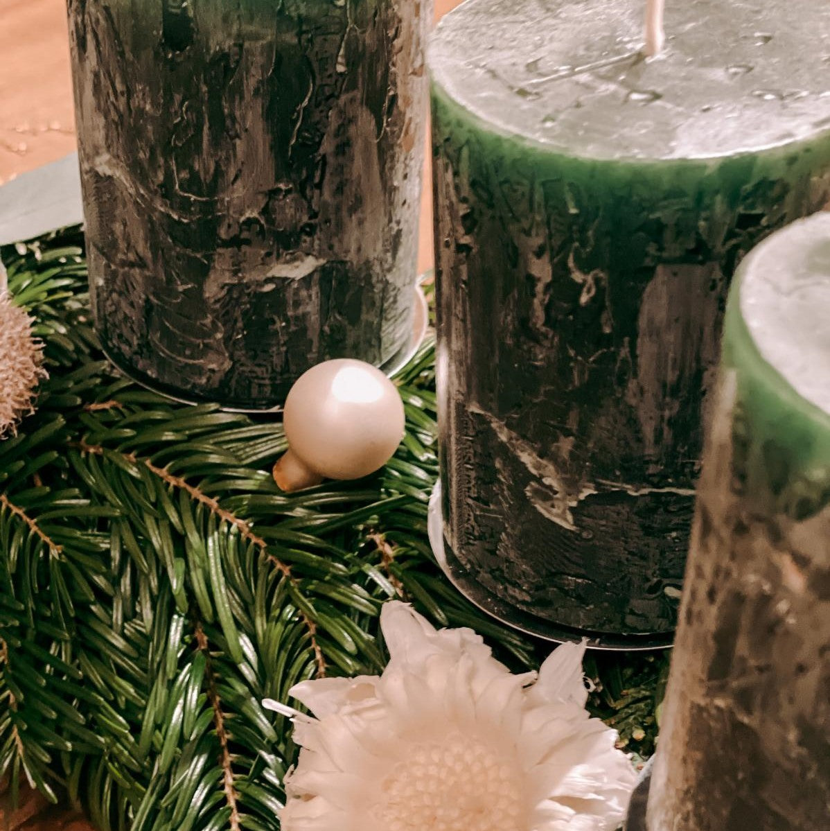 Nahaufnahme von grünen Kerzen auf Kranz mit weißen Blumen – festliche DIY Box Hänsel Dekoration.