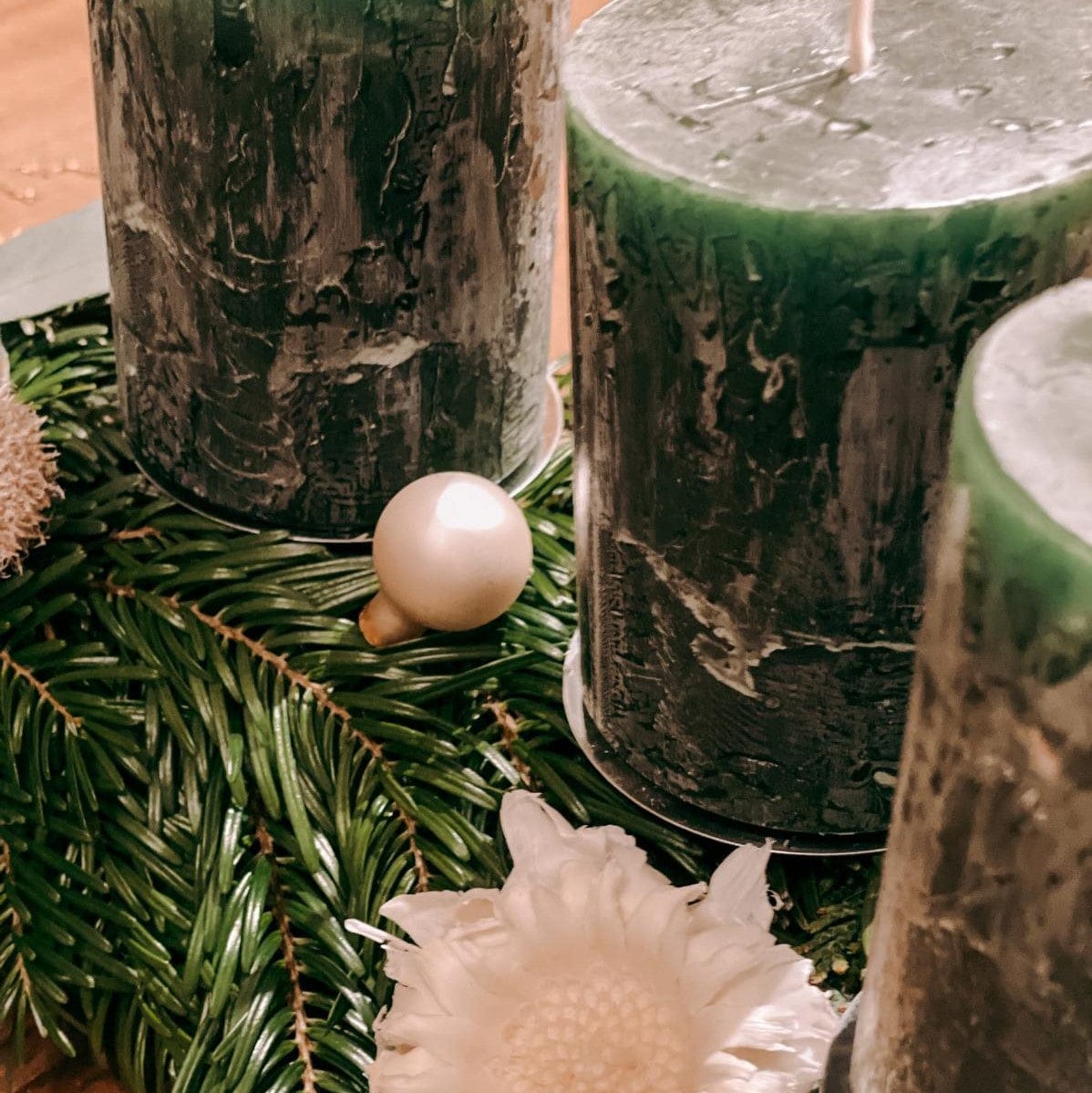 Nahaufnahme von grünen Kerzen auf Kranz mit weißen Blumen – festliche DIY Box Hänsel Dekoration.
