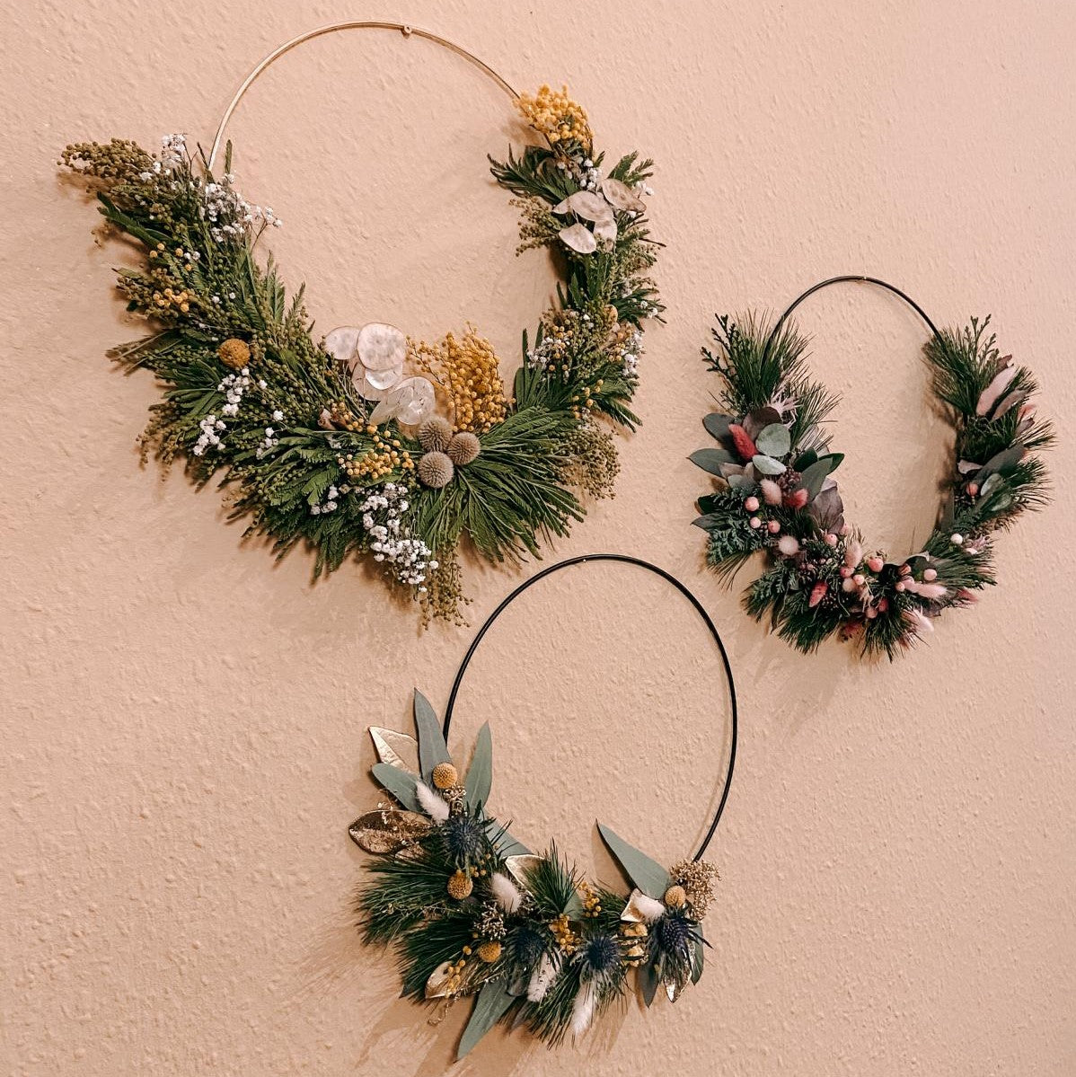 Drei fertige Weihnachtsringe hängen an der Wand – weihnachtsdeko ring, trockenblumen ring.