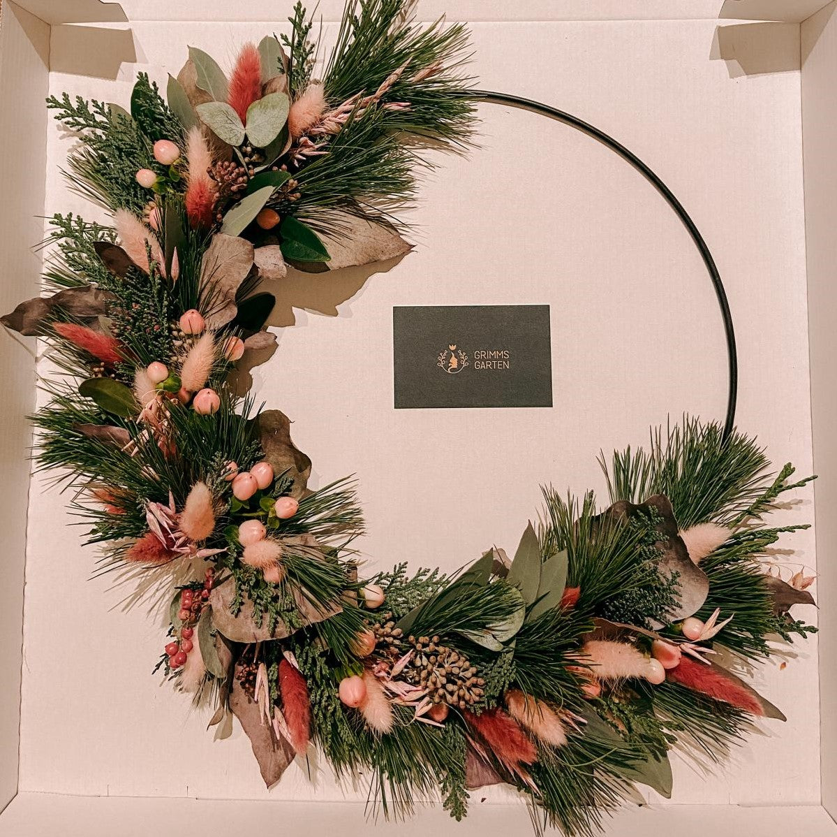 Fertiger Weihnachtsdeko-Ring mit roten und rosa Elementen an der Wand – weihnachtsdeko ring, weihnachtskranz modern.