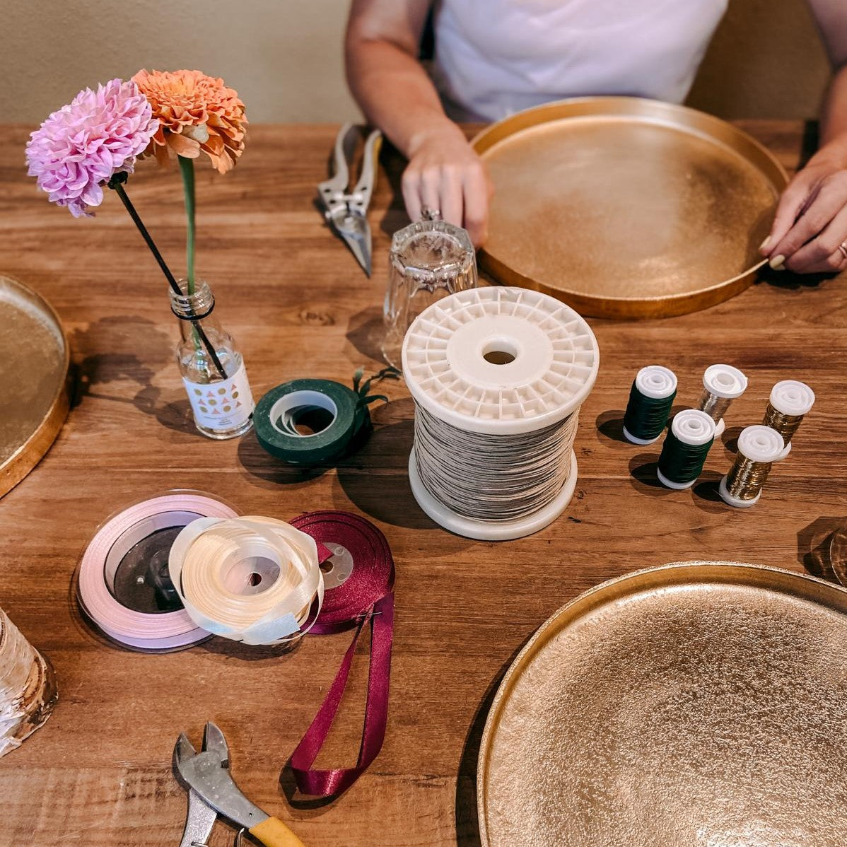Bänder, Scheren und Blumen auf Holztisch – DIY Blumenkrone Workshop, ideal für Firmenevents.