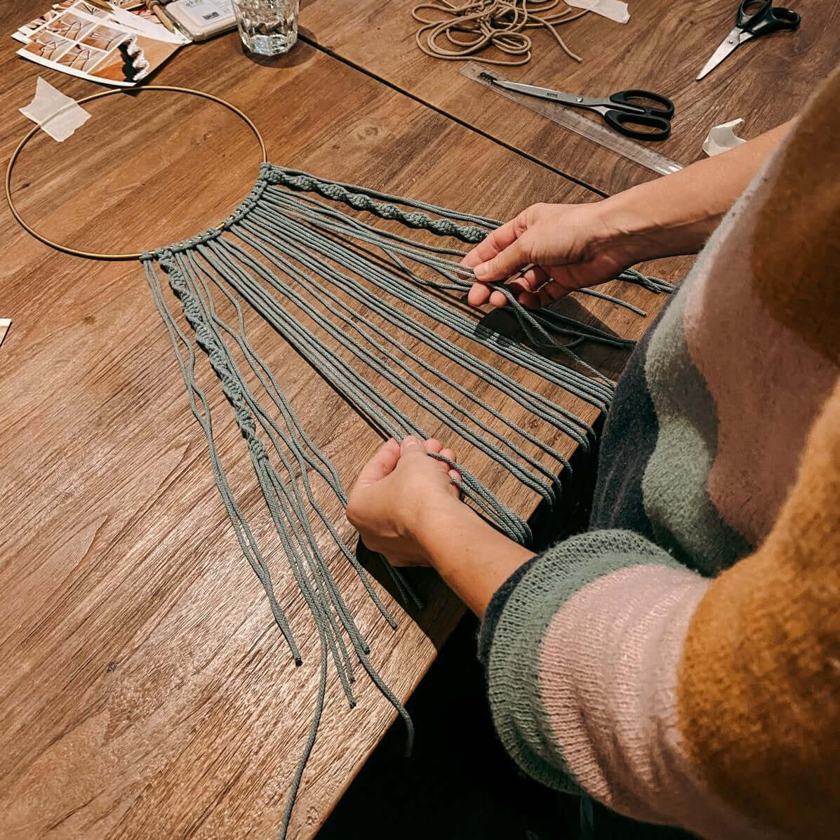 Zwei Hände knoten blaugrauen Makramee-Ring – Handarbeit Detailaufnahme, Makramee Workshop.