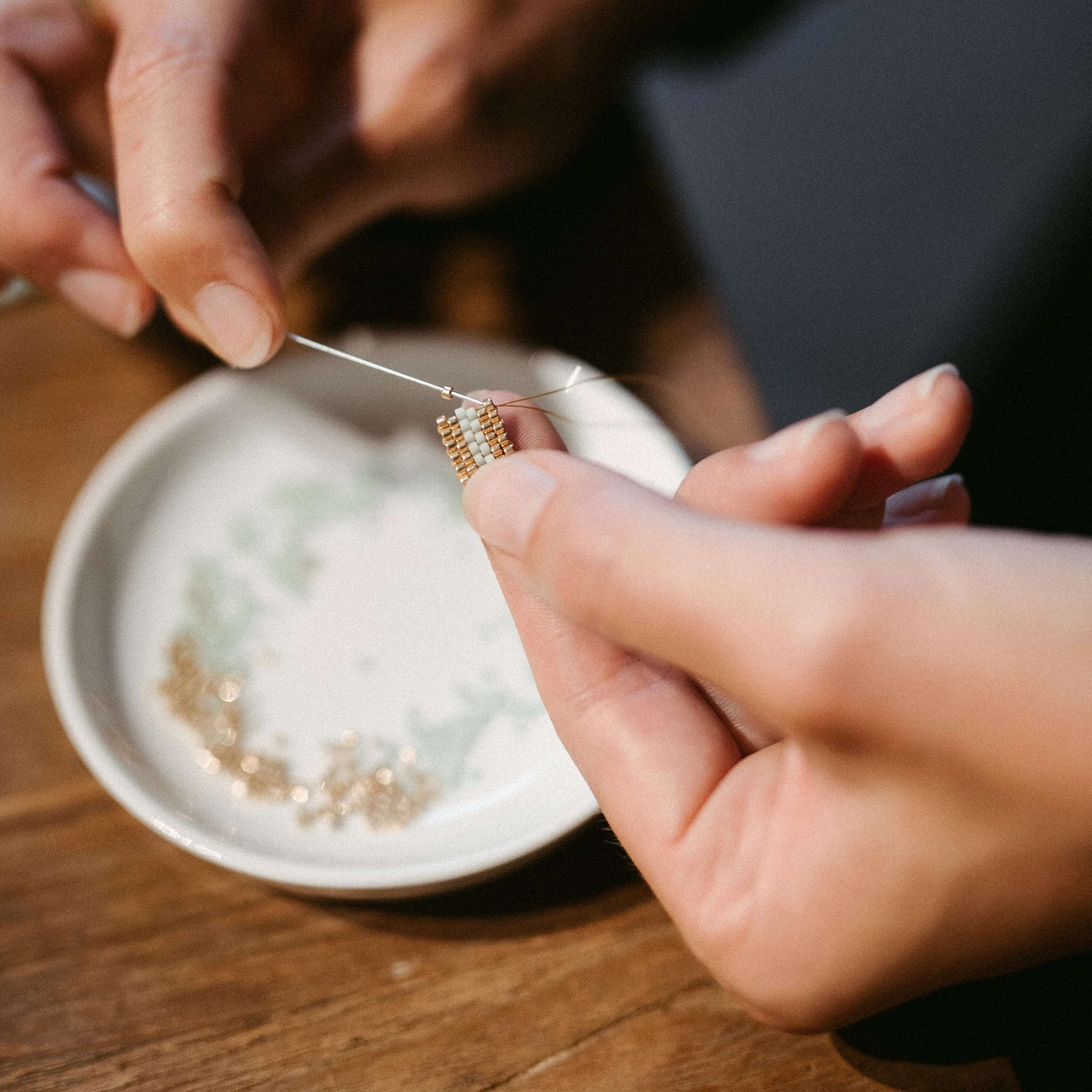Hände fädeln Perlen auf Draht, Nahaufnahme – DIY Fingerring mit japanischen Glasperlen
