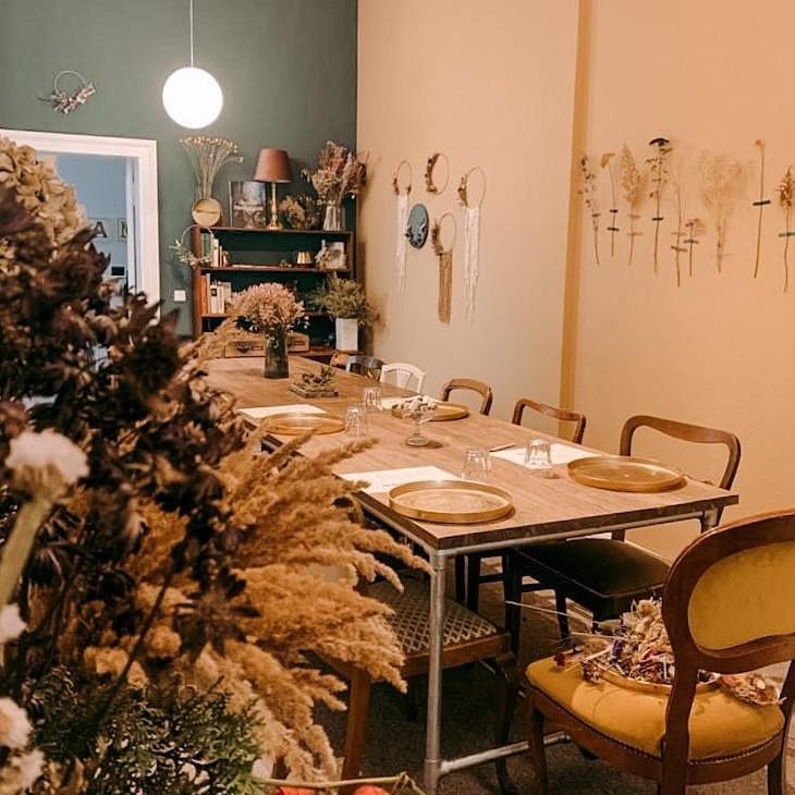 Raum mit großem Tisch und Trockenblumen-Stationen – Workshop Trockenblumenring, Firmenevent, DIY.