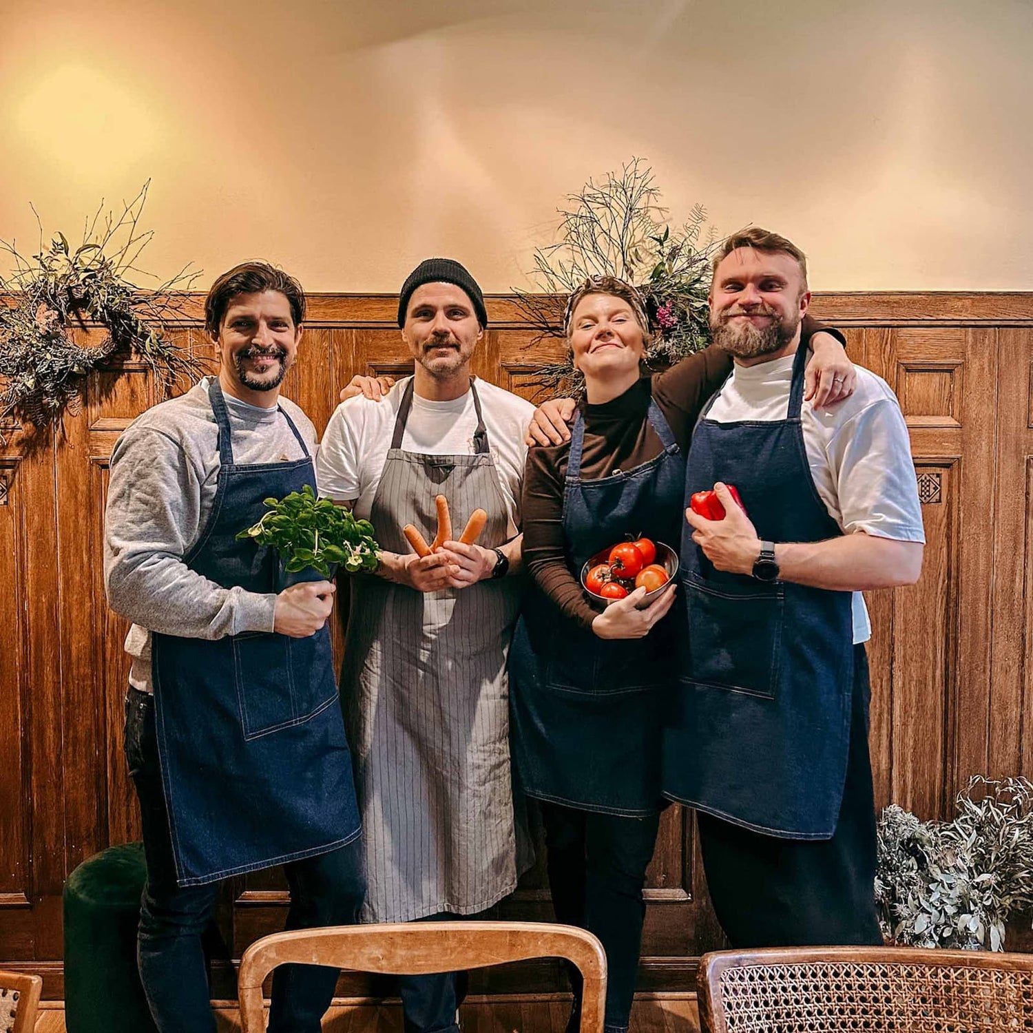 Vier Personen halten frisches Gemüse in den Händen beim gemeinsamen Kochkurs von GRIMMS GARTEN, kreatives Teamevent und Workshop in Berlin