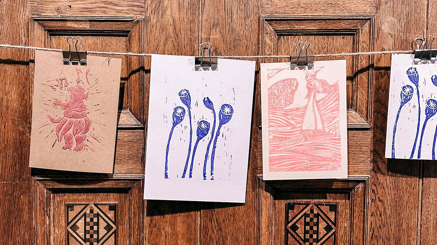 Vier Linolschnitt-Projekte an Schnur hängend – kreativ im GRIMMS GARTEN Workshop gestalten.