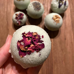 Fertige Badekugeln mit Blüten dekoriert, mehrere im Hintergrund – Badekugel, Badebombe, Entspannung zuhause.