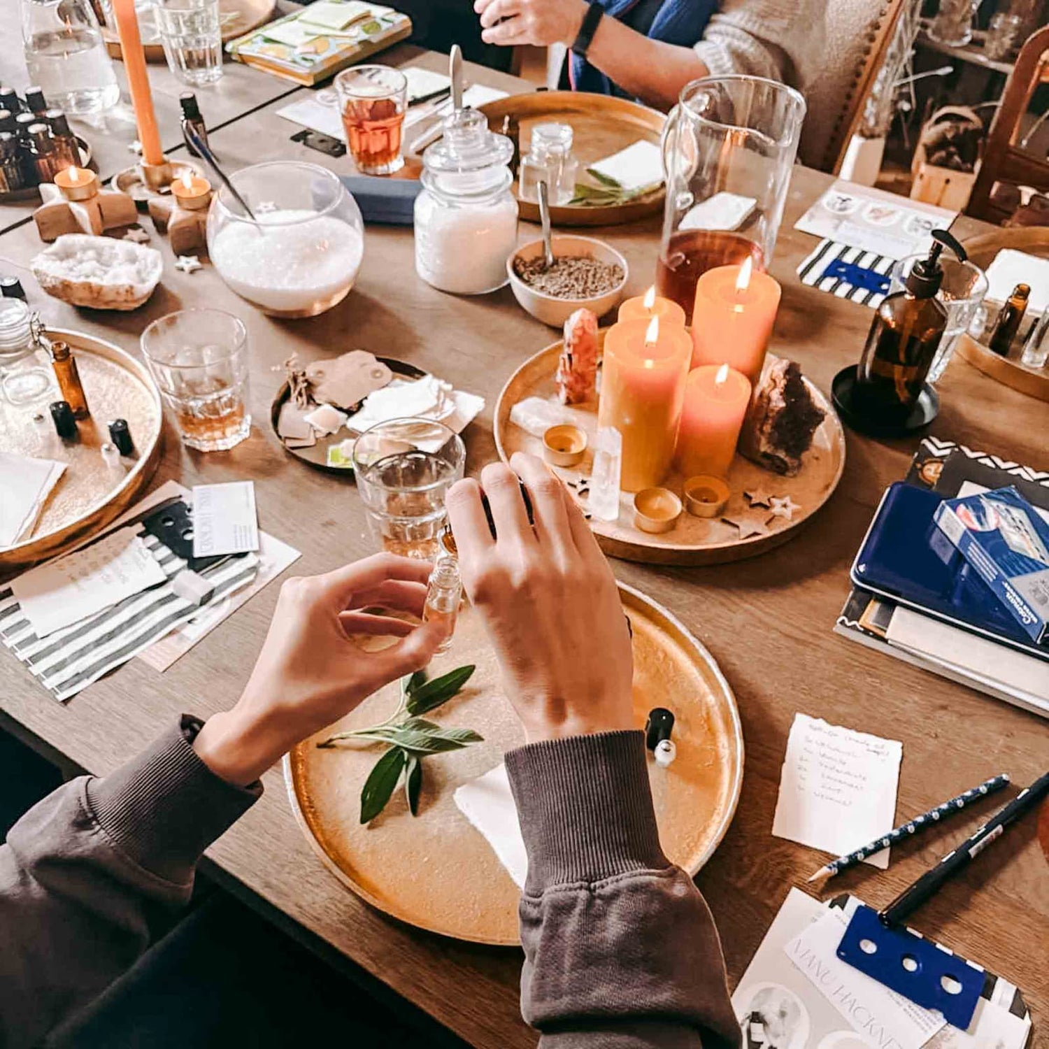 Hände befüllen ein Fläschchen mit Öl, im Hintergrund weitere Materialien für einen spirituellen Workshop