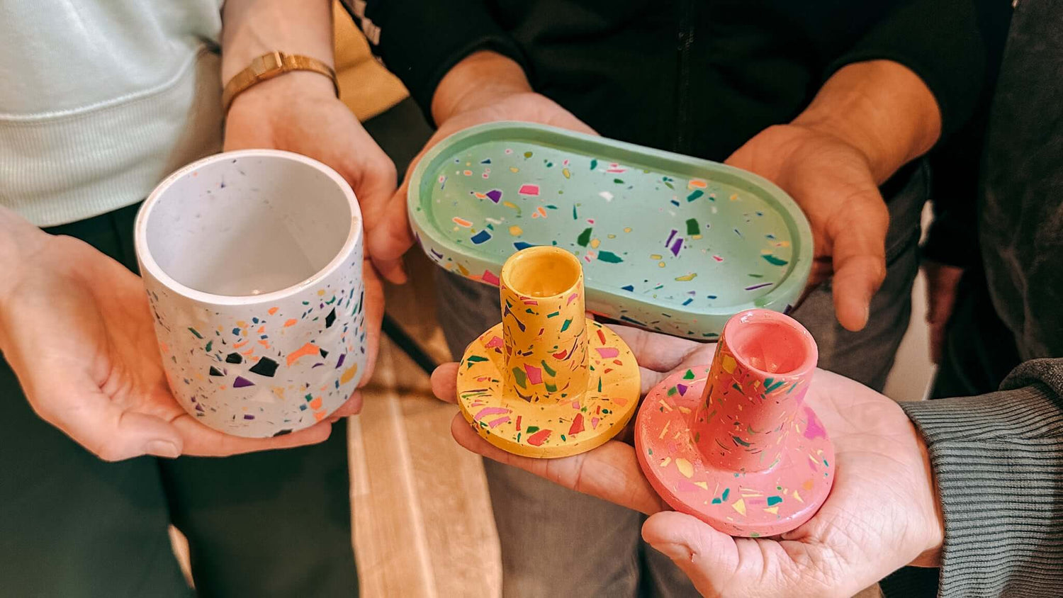 Vier Terrazzo-Projekte, von Teilnehmerhänden gehalten, beim kreativen Workshop von GRIMMS GARTEN.