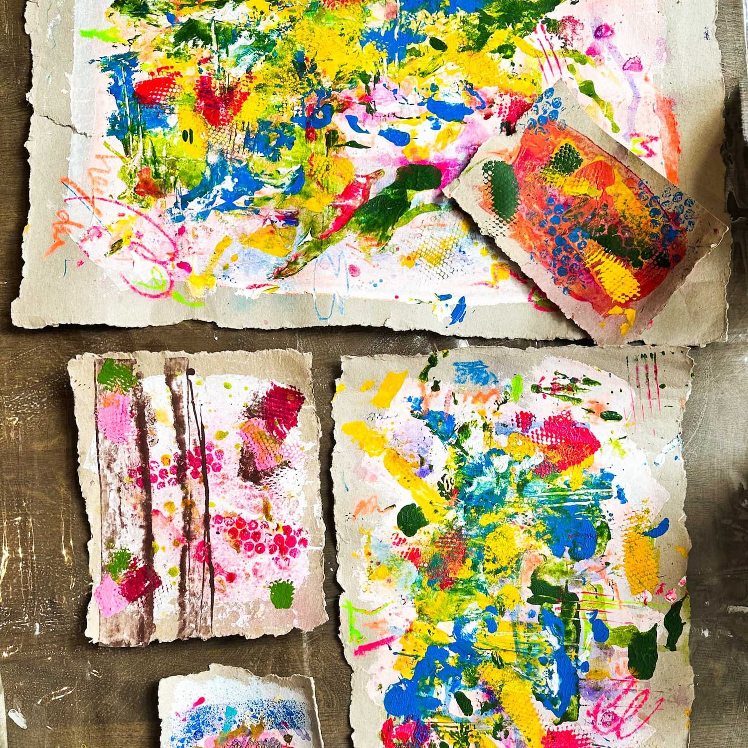 Mehrere bemalte Malpappen mit verschiedenen Acrylfarben auf dem Tisch beim kreativen Abstract Painting Workshop von GRIMMS GARTEN Berlin