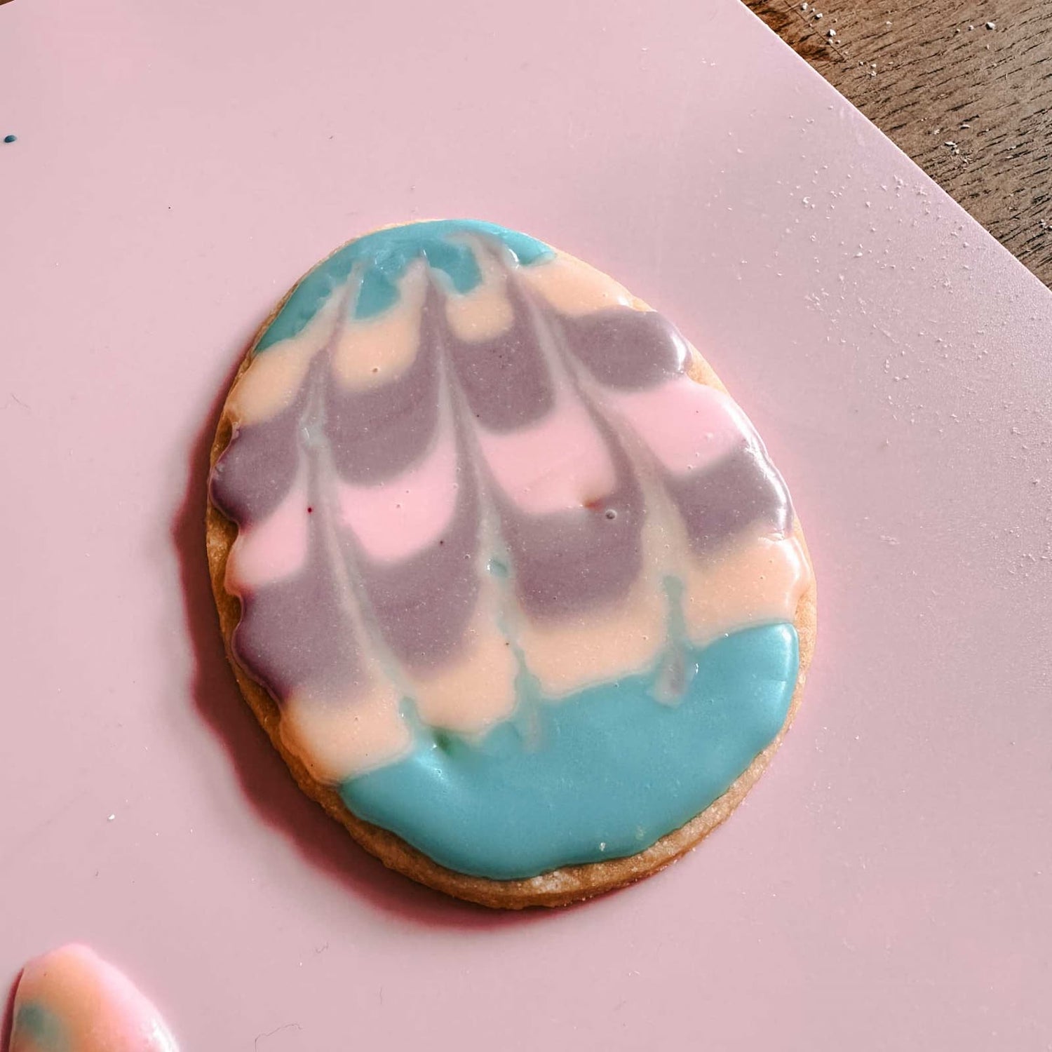 Zuckerguss in farbigen Streifen auf eiförmigem Osterkeks verteilt, mit sanftem Farbverlauf beim Osterkekse Workshop von GRIMMS GARTEN in Berlin