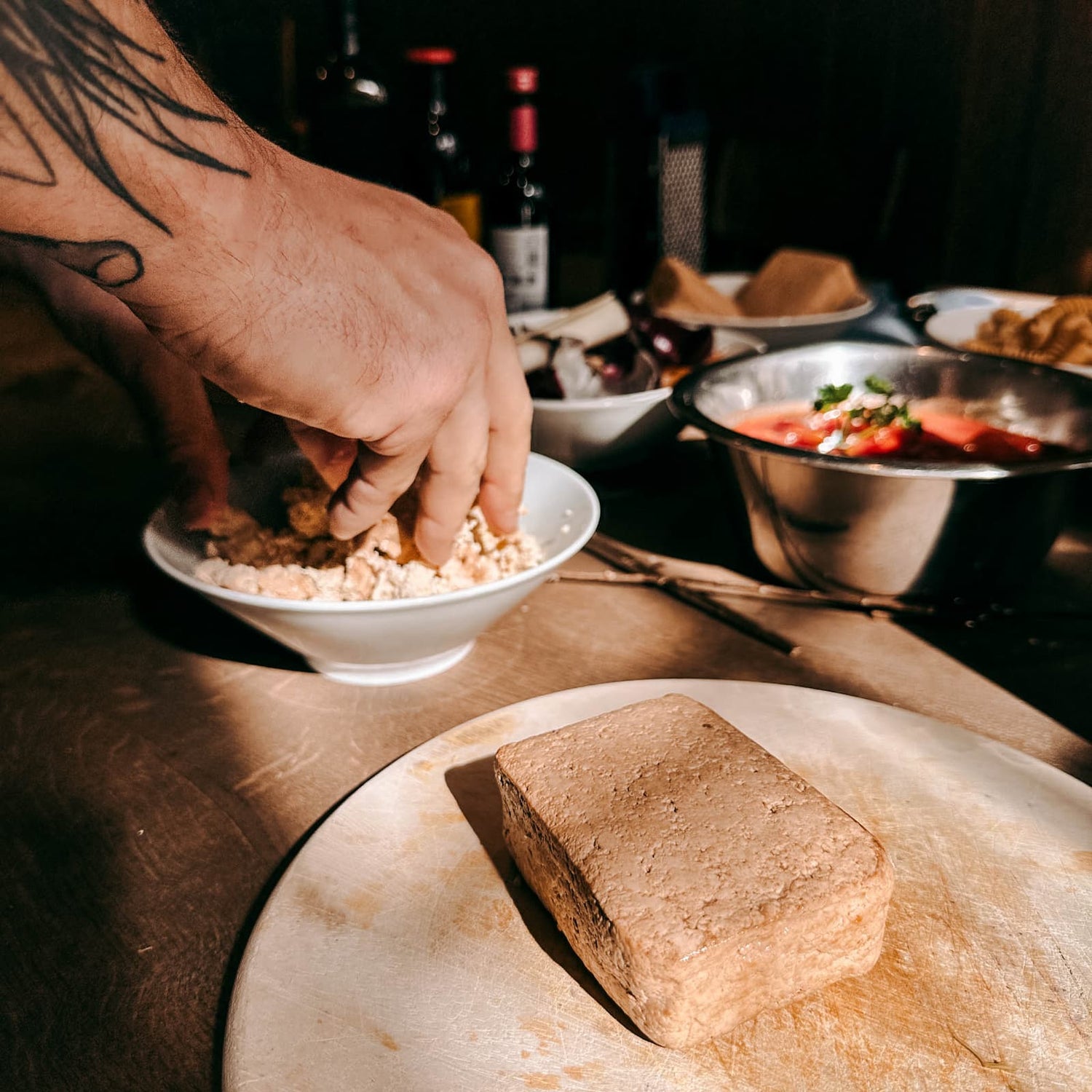 Tofu im Vordergrund, während eine Hand im Hintergrund Tofu zerkrümelt beim Batch Cooking Workshop von GRIMMS GARTEN, Meal Prep Kochkurs in Berlin
