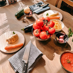 Verschiedene Gemüsesorten mit Tellern, Soßen und Messer auf dem Tisch vorbereitet beim Batch Cooking Workshop von GRIMMS GARTEN, Meal Prep Kochkurs in Berlin