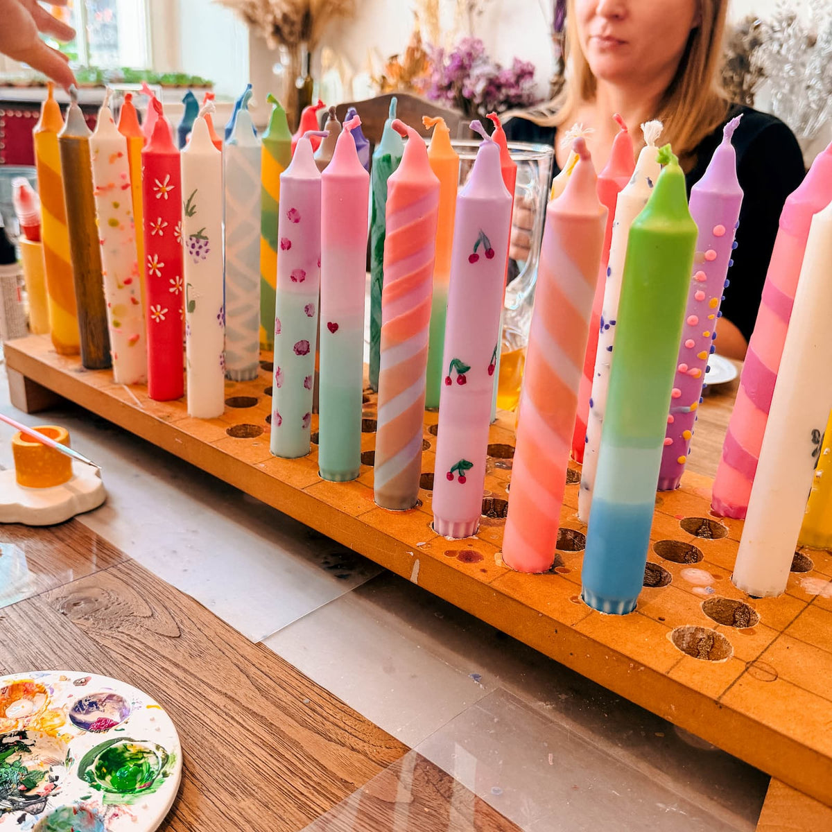 Verschiedene bemalte Dip Dye Kerzen im Kerzenständer beim kreativen Kerzen Workshop und Team Event von GRIMMS GARTEN in Berlin