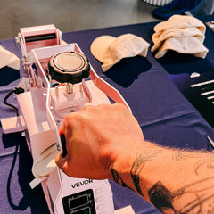 Hand presst Stickmaschine auf Cap beim kreativen Caps besticken Workshop von GRIMMS GARTEN Berlin