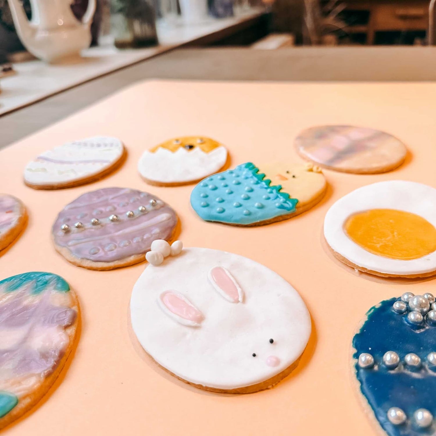 Viele verschieden dekorierte Osterkekse mit unterschiedlichen Motiven auf Tisch und pinker Backmatte beim Osterkekse Workshop von GRIMMS GARTEN in Berlin