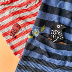 Roter Vogel auf rot-grau gestreiftem Shirt und schwarzer Vogel auf blau-schwarz gestreiftem Shirt beim Patches nähen Workshop von GRIMMS GARTEN in Berlin