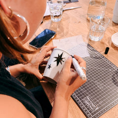 Frau malt schwarze Sterne auf Kaffee To Go Becher beim kreativen Becher Workshop und Team Event von GRIMMS GARTEN