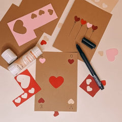 Ausgeschnittene Herzchen in verschiedenen Farben mit Stift und Postkarten als Bastelmaterial auf dem Tisch beim kreativen Postkarten Workshop von GRIMMS GARTEN in Berlin