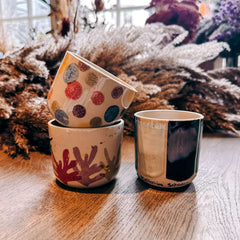 Fertig bemalte Keramik‑Tassen gestapelt auf Tisch – Keramik Workshop Berlin, individuelles Keramikhandwerk