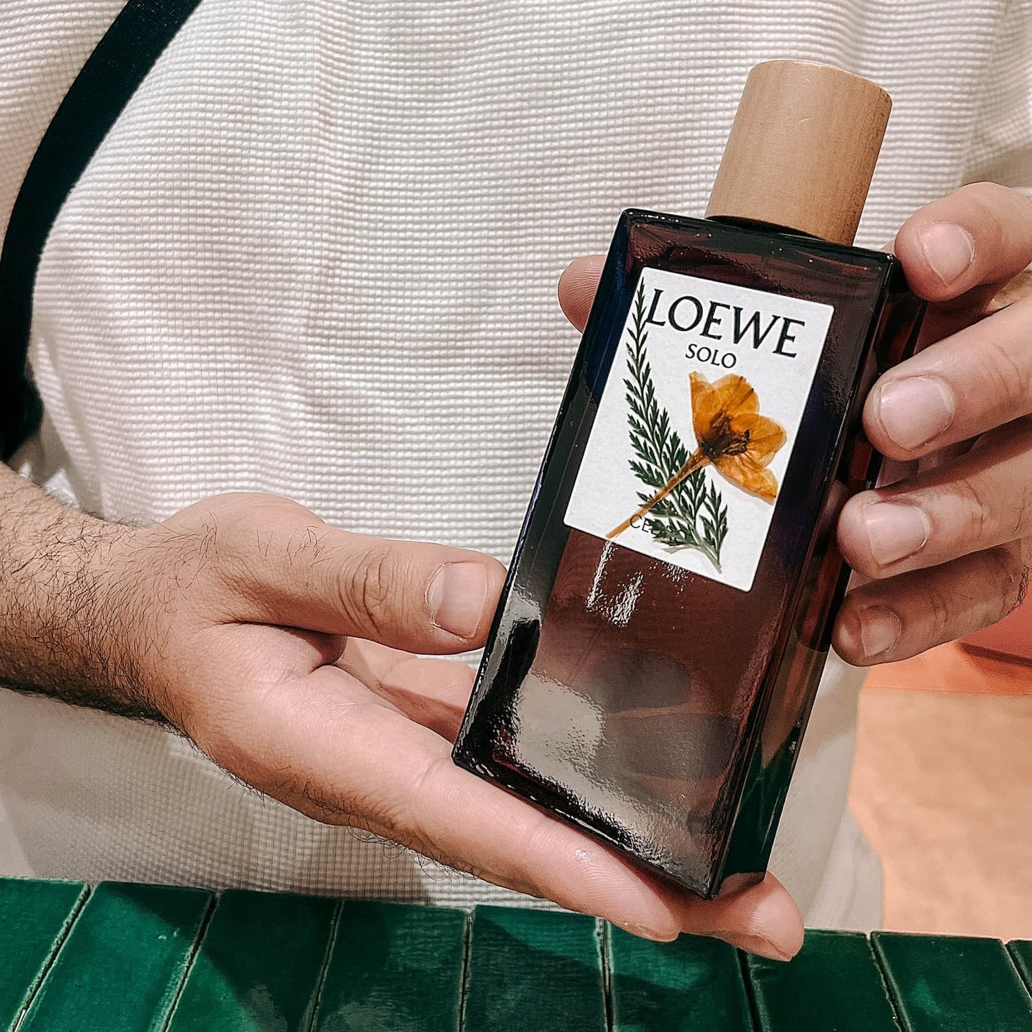 Zwei Hände halten fertig dekoriertes Parfum mit Trockenblumen im DIY Workshop von GRIMMS GARTEN Berlin
