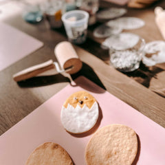 Küken in Eierschale als dekorierter Osterkeks neben zwei unfertigen Keksen und Fondantrolle auf dem Tisch beim Osterkekse Workshop von GRIMMS GARTEN in Berlin