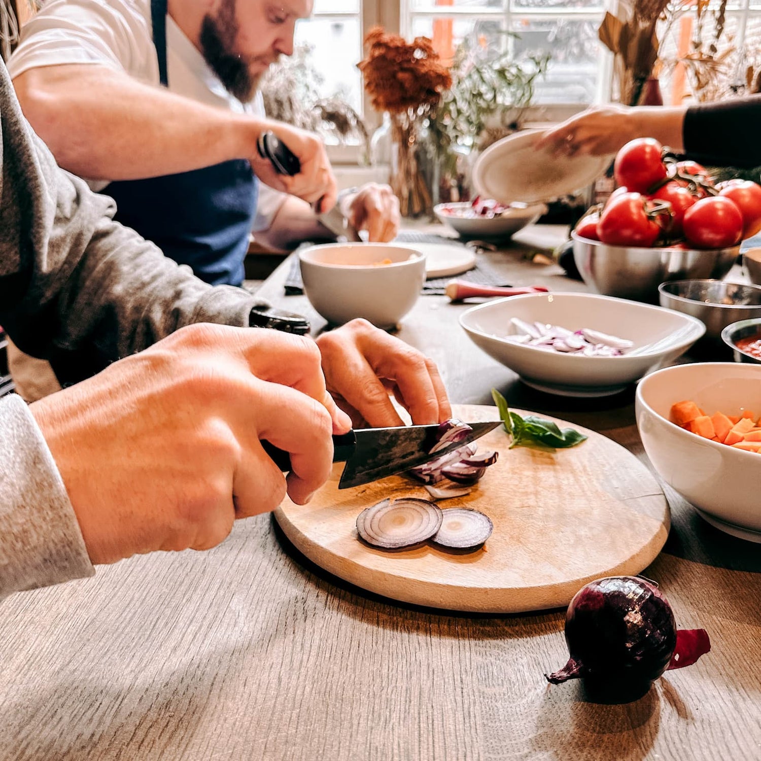 Hände schneiden Zwiebel in feine Scheiben beim Batch Cooking Workshop von GRIMMS GARTEN, Meal Prep Kochkurs in Berlin
