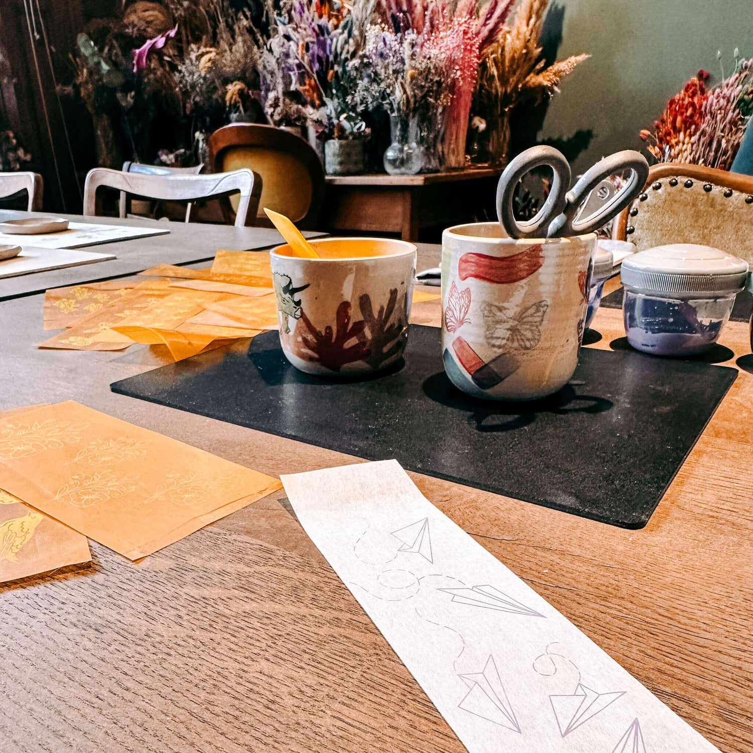 Zwei Keramikbecher auf Tisch mit Schere und Papier – kreativer Keramik Workshop in Berlin, DIY Keramik bemalen