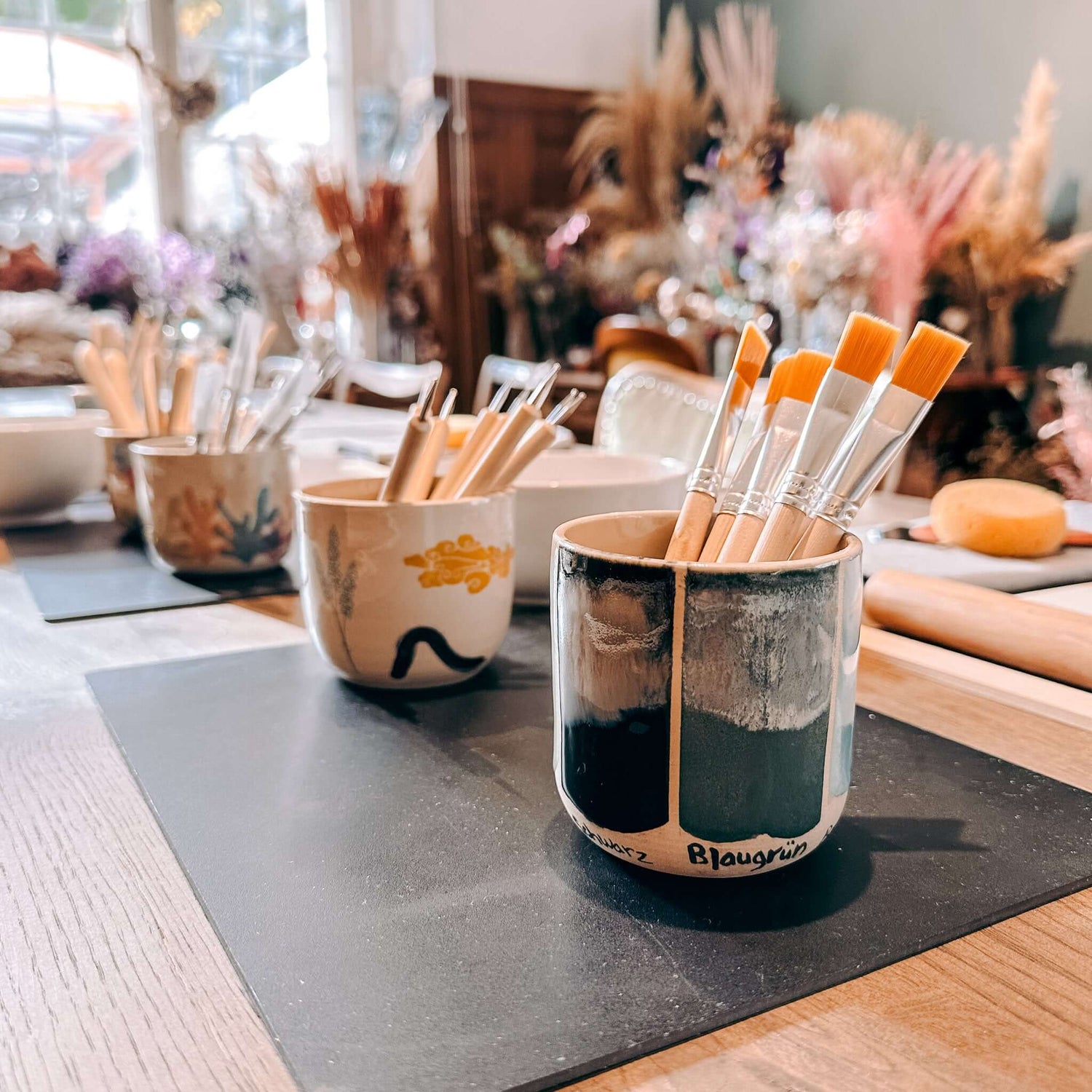 Bunte Glasurbehälter mit Pinseln auf Tisch bereitgestellt – Farbauswahl im Keramik Workshop Berlin
