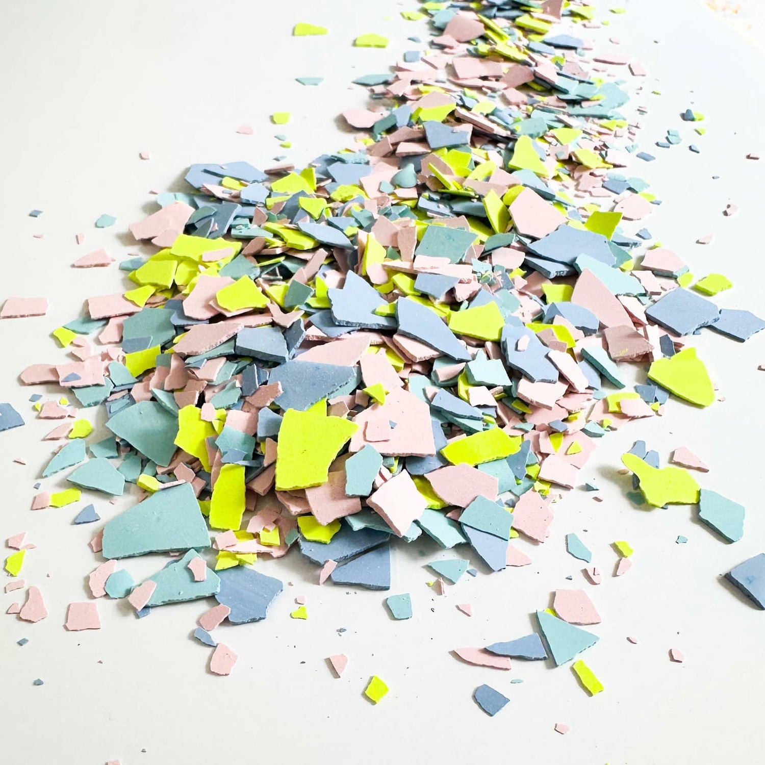 Terrazzo-Chips in Grün, Blau und Pink liegend und verteilt für kreativen Workshop