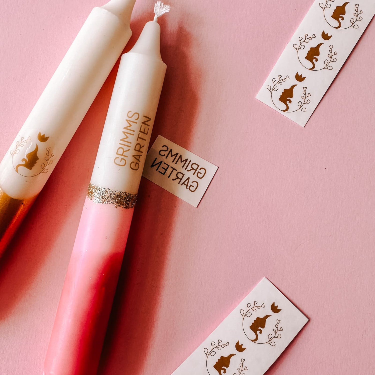 Zwei pinke Kerzen mit goldenen Logos gestaltet beim Kerzen Tattoo Workshop von GRIMMS GARTEN, kreatives Teamevent in Berlin