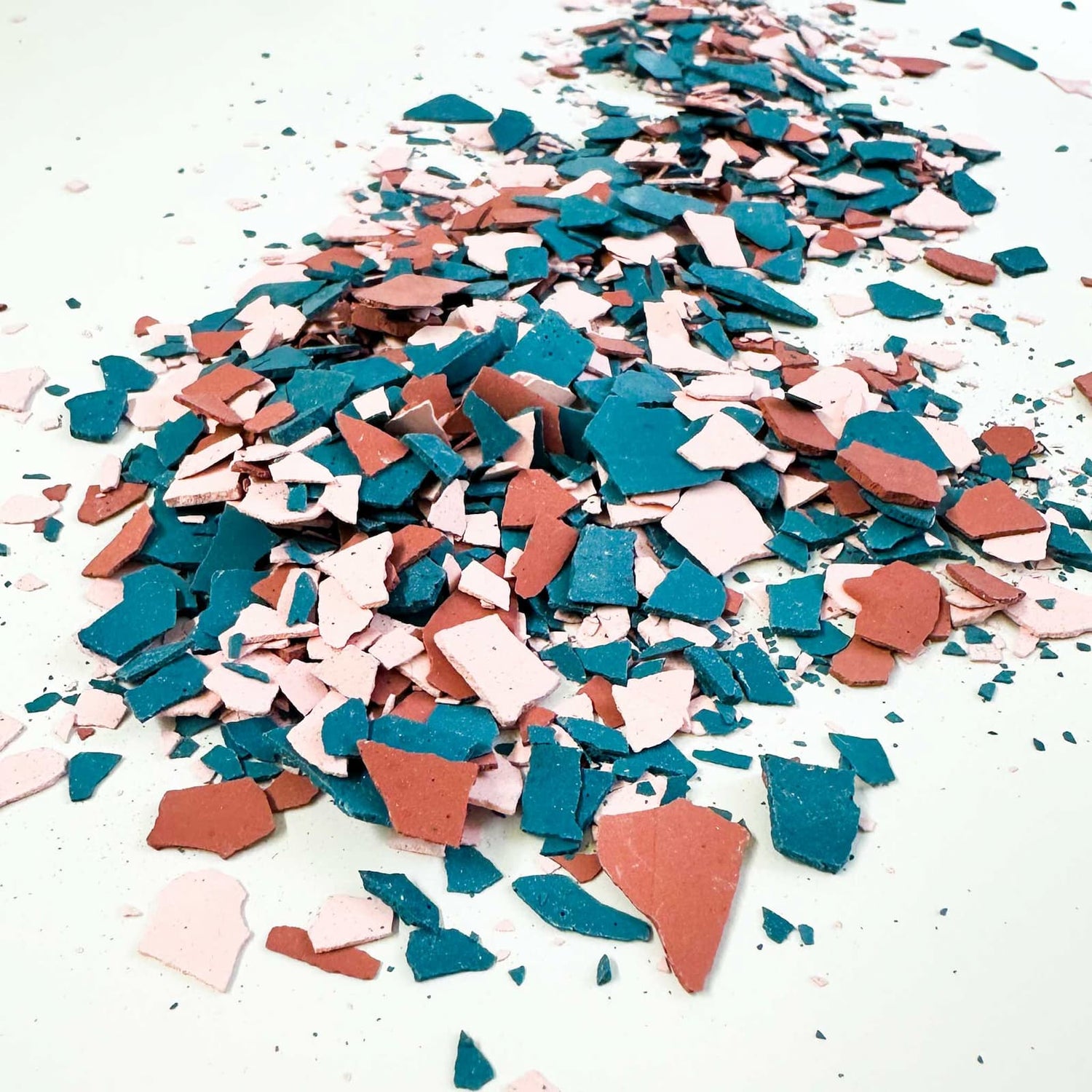 Terrazzo-Chips in Blau, Pink und Rot für kreativen Workshop dekorativ auf der Arbeitsfläche verteilt
