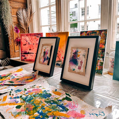 Zwei abstrakt bemalte Malpappen in Bilderrahmen, davor weitere kreative Kunstwerke beim Acryl Workshop von GRIMMS GARTEN Berlin