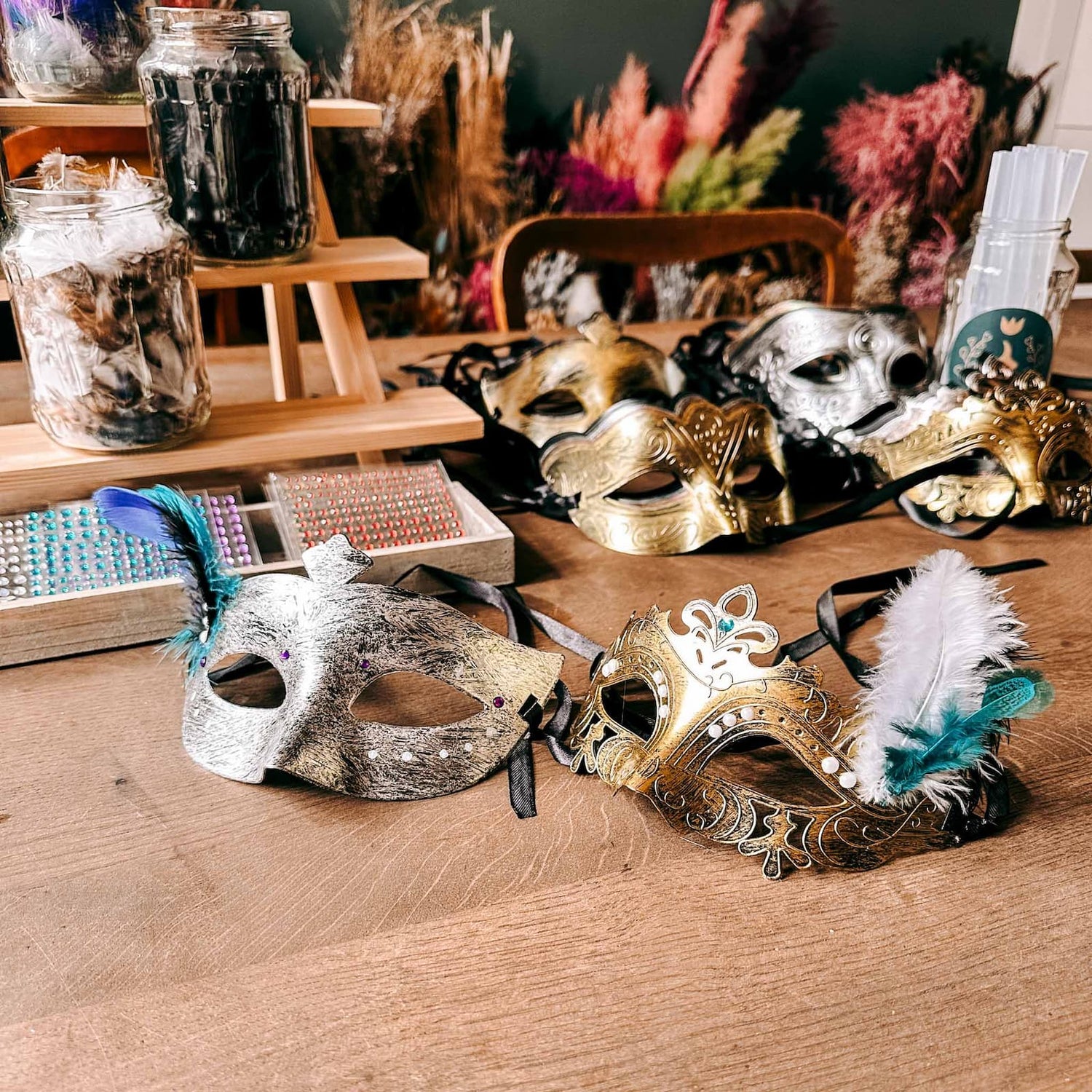 Viele verschiedene DIY Masken mit bunten Farben und dekorativen Elementen auf Holztisch beim kreativen Workshop von GRIMMS GARTEN, Teamevent in Berlin