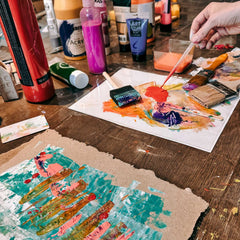 Pipette mit roter Acrylfarbe neben blau bemalter Malpappe und kreativen Materialien beim Abstract Painting Workshop von GRIMMS GARTEN Berlin