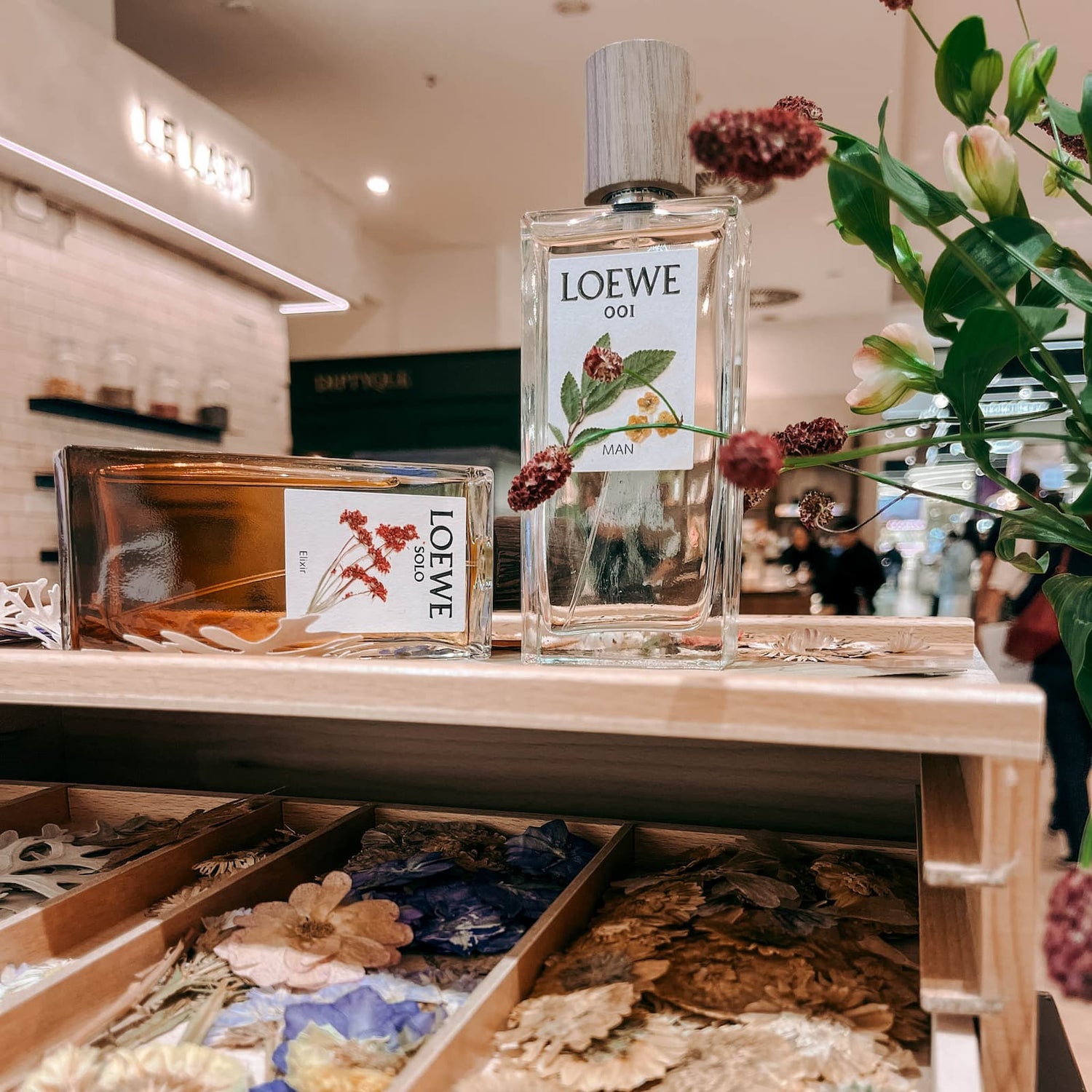 Zwei Parfum Flakons auf Holzständern mit Trockenblumen dekoriert im Kreativ Workshop von GRIMMS GARTEN Berlin