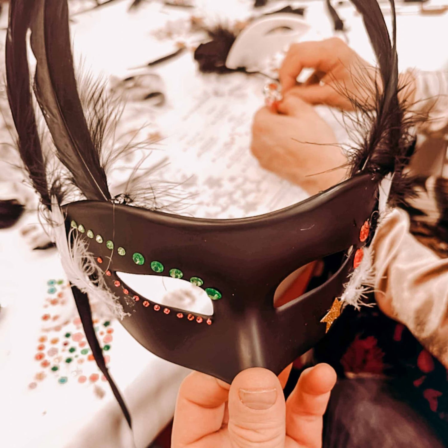 Schwarze DIY Maske mit grünen und pinken Glitzersteinen beim kreativen Masken Workshop von GRIMMS GARTEN, Teamevent in Berlin