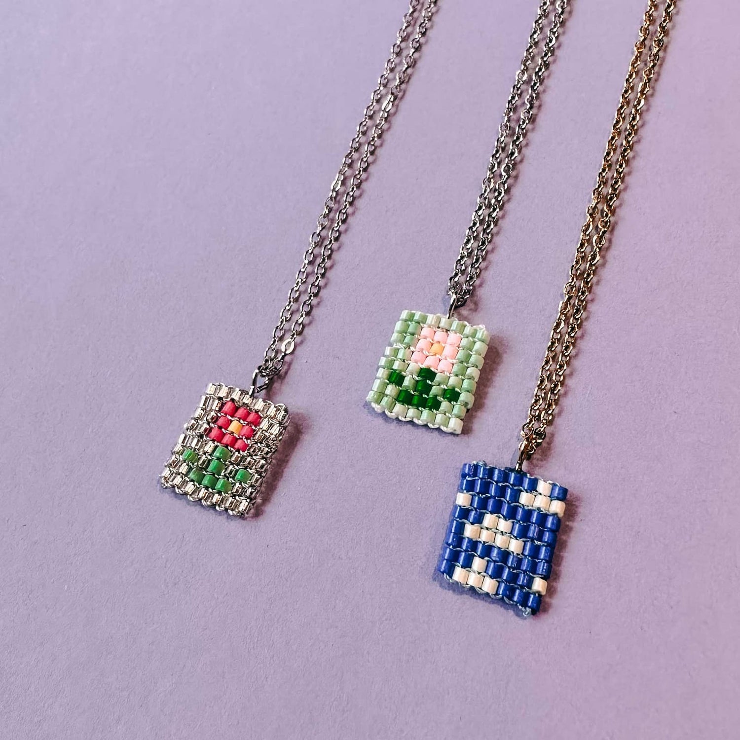 Drei fertige Perlenketten mit Anhängern – zwei mit Blumenmotiv und eine mit Himmel und Wolke – aus dem DIY Perlenschmuck Workshop von GRIMMS GARTEN in Berlin