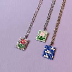 Drei fertige Perlenketten mit Anhängern – zwei mit Blumenmotiv und eine mit Himmel und Wolke – aus dem DIY Perlenschmuck Workshop von GRIMMS GARTEN in Berlin