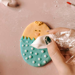 Hand setzt blaue Zuckerguss-Punkte mit Spritztüte auf Osterkeks beim Osterkekse Workshop von GRIMMS GARTEN, kreativer Backkurs in Berlin