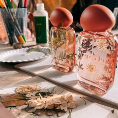 Zwei Parfum Flakons mit Trockenblumen dekoriert, davor liegen bunte Blüten im Workshop von GRIMMS GARTEN Berlin