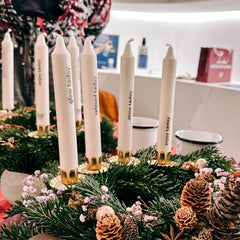 Vier Kerzen mit unterschiedlichen Schriftzügen auf weißem Adventskranz beim Kerzen Tattoo Workshop von GRIMMS GARTEN, kreatives Teamevent in Berlin