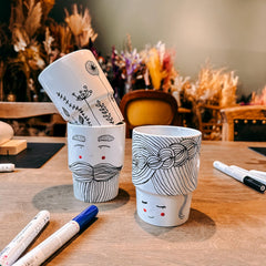Drei Keramik To-Go Becher mit Motiven – Paar mit Frau, Mann und Blumenwiese – beim Keramik bemalen Workshop von GRIMMS GARTEN, Kreativkurs in Berli