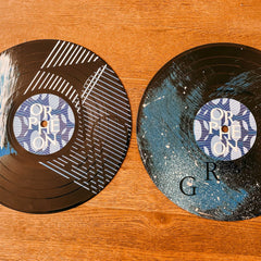 Zwei bemalte Schallplatten mit unterschiedlichen Farbstrichen und Mustern auf dem Tisch beim Vinylplatten bemalen Workshop von GRIMMS GARTEN, Kreativkurs in Berlin