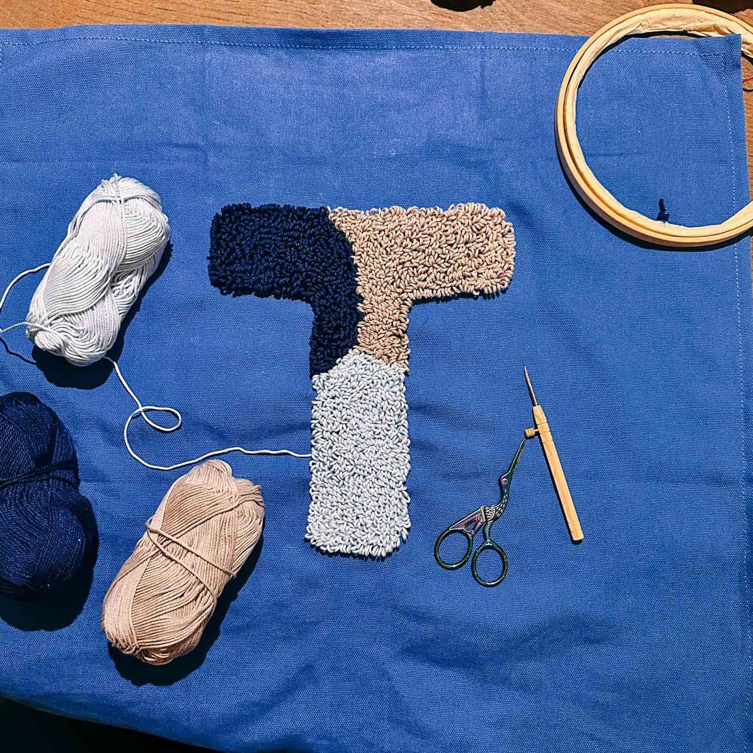 Blaues Tuch mit ‚T‘ in Hell- und Dunkelblau gestickt – Punch Needle Workshop bei Grimms Garten